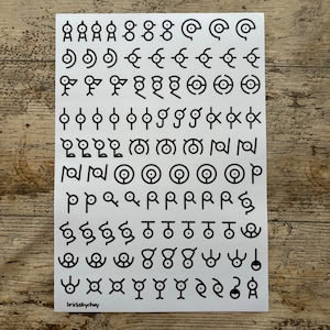 May include: A white sheet of paper with black symbols printed on it. The symbols are various shapes and designs, including circles, squares, and triangles. The text "bricksbychay" is printed in the bottom left corner.