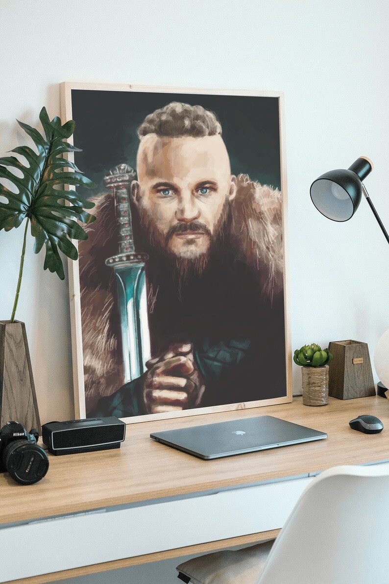 May include: A framed poster of a man with a beard and a shaved head, holding a sword. He is wearing a fur-lined coat and has a serious expression on his face. The background is dark.