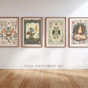 May include: Four framed art prints with dragon illustrations. Each print has a gold frame and shows a different dragon scene: reading, holding a torch, holding a heart, and sleeping by a fire. The text "FOLK AND FOREST ART" is below the prints.