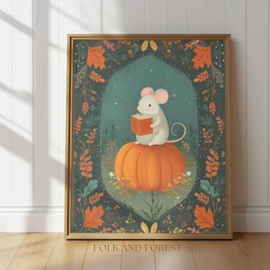 Op de afbeelding: Een ingelijste kunstdruk met een grillige illustratie van een witte muis die een boek leest terwijl hij op een grote oranje pompoen zit. Het kunstwerk is geplaatst tegen een teal-kleurige achtergrond met herfstbladeren en een decoratieve rand. De tekst "FOLK AND FOREST ART" staat onderaan.