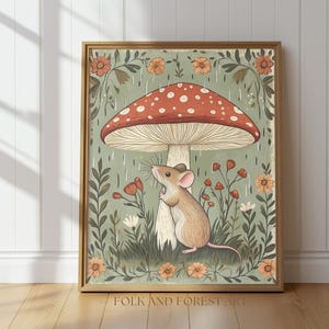 Puede incluir: Una impresi&oacute;n art&iacute;stica enmarcada que presenta una ilustraci&oacute;n caprichosa de un rat&oacute;n debajo de una gran seta con un sombrero rojo y puntos blancos. La obra de arte tiene una paleta de colores suaves con elementos florales y de follaje. El texto "FOLK AND FOREST ART" est&aacute; en la parte inferior.