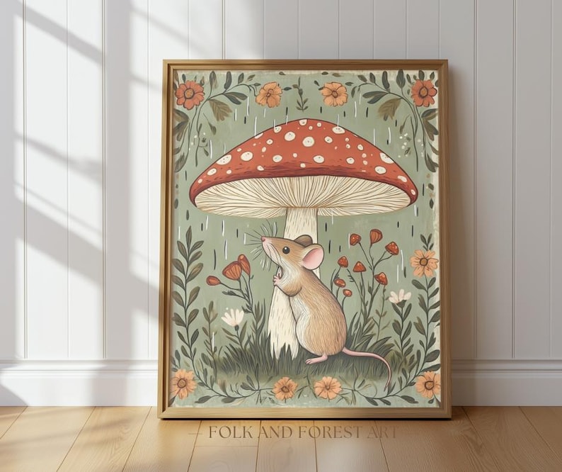 Puede incluir: Una impresi&oacute;n art&iacute;stica enmarcada que presenta una ilustraci&oacute;n caprichosa de un rat&oacute;n debajo de una gran seta con un sombrero rojo y puntos blancos. La obra de arte tiene una paleta de colores suaves con elementos florales y de follaje. El texto "FOLK AND FOREST ART" est&aacute; en la parte inferior.