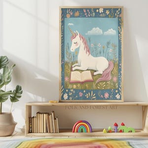 May include: A framed art print featuring a white unicorn with a pink mane and tail, reading a book in a field of flowers. The artwork has a blue background with clouds and a decorative floral border. The text "FOLK AND FOREST ART" is visible.
