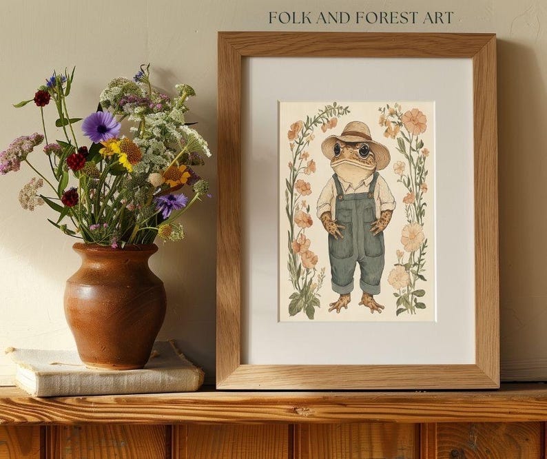 May include: A framed illustration of a frog wearing a straw hat and overalls standing in a field of flowers. The illustration is titled "Folk and Forest Art".