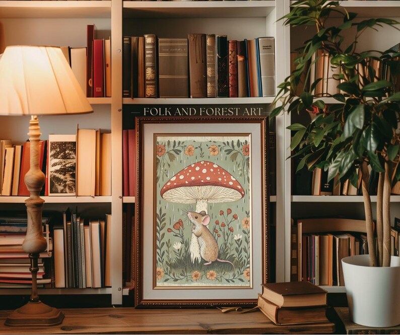Puede incluir: L&aacute;mina art&iacute;stica enmarcada con una ilustraci&oacute;n caprichosa de un rat&oacute;n bajo una seta roja y blanca con lunares. La obra de arte, etiquetada como "FOLK AND FOREST ART", est&aacute; ambientada sobre un fondo de flores y follaje, con un marco de madera.