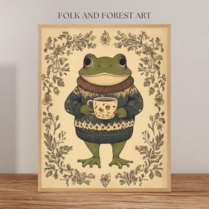 Puede incluir: Una rana verde con un suéter azul y blanco sostiene una taza de café en su mano. La rana está rodeada de un patrón floral.