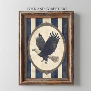 Pode incluir: Uma impressão emoldurada com um fundo listrado azul e branco. Uma moldura oval de estilo vintage apresenta uma ilustração em preto e branco de uma águia careca em voo. O texto "FOLK AND FOREST ART" está impresso na parte superior da moldura.