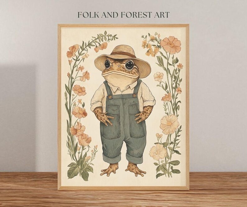 May include: A whimsical illustration of a toad wearing a straw hat and overalls, surrounded by delicate wildflowers in shades of pink and yellow. The toad is smiling and has a friendly expression. The artwork is framed in a light wood frame.