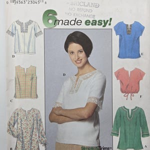 Può includere: Un modello di cucito Simplicity con sei diversi modelli di camicetta. L'immagine mostra una donna che indossa una camicetta bianca con finiture in pizzo. Il modello include vari stili, con opzioni a maniche corte e lunghe, in diversi colori e fantasie.