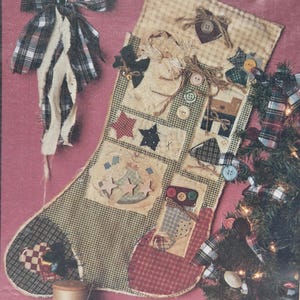 May include: A handmade Christmas stocking with a patchwork design, featuring various fabric patterns and embellishments like stars, hearts, and buttons. The stocking is decorated with a plaid bow and is next to a small Christmas tree.
