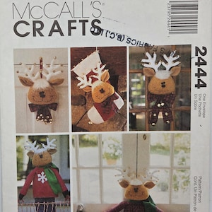 May include: McCall's Crafts pattern envelope 2444 featuring sewing instructions for reindeer-themed holiday decorations. The images show plush reindeer heads with white antlers, a Christmas stocking, and full-body reindeer figures wearing sweaters.
