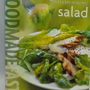 May include: A cookbook cover with the title "FOODMADEFAST" in large, vertical white letters. The cover features a salad with grilled chicken, romaine lettuce, and parmesan cheese. The words "WILLIAMS-SONOMA" and "salad" are also visible.