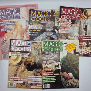 May include: A selection of vintage "Magic Crochet" magazines. The covers display vibrant text and images of crochet projects, such as afghans, home decor, and clothing. The magazines are stacked, highlighting various issues with different themes and designs.