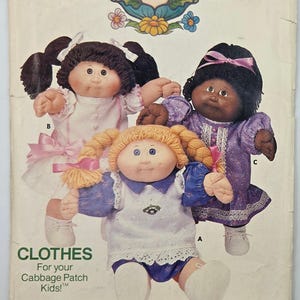 May include: Vintage Butterick sewing pattern featuring Cabbage Patch Kids dolls. The cover displays three dolls in various outfits. The text reads "CLOTHES For your Cabbage Patch Kids!" and the pattern number is 6934.
