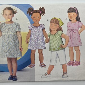Può includere: Un modello di cucito con illustrazioni di quattro ragazze in diversi outfit. Gli outfit includono abiti e un top con pantaloncini. Gli abiti hanno motivi floreali e tinta unita. Le ragazze sono in varie pose.