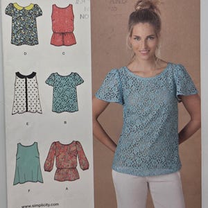 May include: Simplicity sewing pattern with multiple blouse designs. The pattern includes options with short and long sleeves, and different necklines. The image also shows a woman wearing a light blue lace top. The pattern size is Euro 30-38.