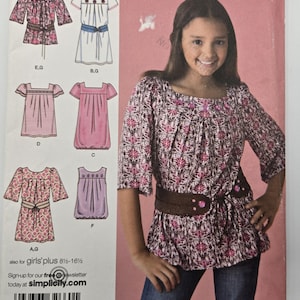 May include: Simplicity sewing pattern for girls' tops and dresses. The pattern includes multiple designs with varying sleeve lengths and styles. The cover features a girl wearing a floral top with a brown belt and jeans. The pattern is for sizes 8 1/2 to 16 1/2.
