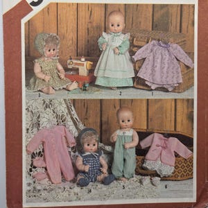 Peut inclure: Image vintage présentant des poupées et leurs vêtements. Les poupées portent des robes, des barboteuses et une veste. Les vêtements sont de couleurs pastel, avec des motifs floraux et rayés. L'arrière-plan comprend un mur en bois et une machine à coudre.