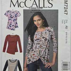 May include: McCall's M7247 sewing pattern. The image shows a woman wearing a long-sleeved top with an asymmetrical design. The pattern includes options for tops with various sleeve lengths and styles. Size A5 (6-8-10-12-14).