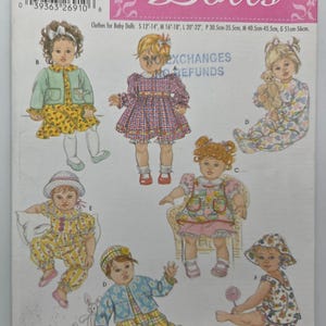 Peut inclure: Un patron de couture pour vêtements de poupées. La couverture présente des illustrations de poupées dans diverses tenues, notamment des robes, des pyjamas et une veste. Le texte "Dolls" est dans une police décorative, avec des informations de taille.