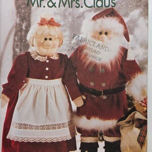 May include: A fabric pattern showing Mr. and Mrs. Claus dolls. Mrs. Claus is in a red dress with a white apron and bow. Mr. Claus wears a red suit with a white beard and hat. The text "Meet Mr. & Mrs. Claus" is at the top of the image.