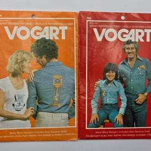 May include: Two vintage Vogart iron-on transfer pattern packets. The orange packet features a couple, the red packet features a father and son. Both packets have the Vogart logo and text about embroidery and ball point painting.
