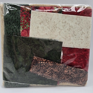 May include: A selection of patterned fabrics in a clear plastic wrapper. The fabrics display floral, berry, and abstract designs in shades of green, red, cream, and brown. Suitable for quilting or other sewing crafts.