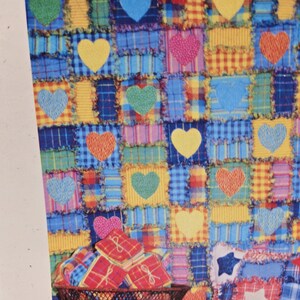 May include: A colourful patchwork quilt featuring squares in blue, yellow, red, and pink, with heart shapes stitched onto them. The quilt's design is a repeating pattern of squares and hearts, creating a vibrant textile.