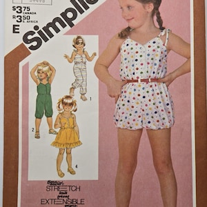 Könnte beinhalten: Simplicity-Schnittmusterumschlag mit einem jungen Mädchen in einem gepunkteten Strampler mit braunem Gürtel. Der Umschlag enthält Illustrationen von Kinderbekleidung und den Text "Stretch Extensible".
