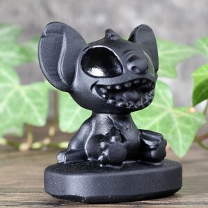 May include: Black Stitch figurine with a wide grin and one eye closed. The figurine is sitting on a black base.