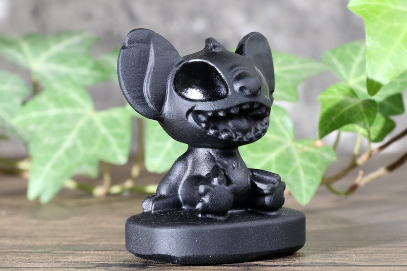 May include: Black Stitch figurine with a wide grin and one eye closed. The figurine is sitting on a black base.