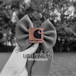 May include: Gray fabric bow with a Carhartt logo patch. The bow is textured and has a classic shape. The Carhartt patch is brown with a black logo and the brand name. The text "Little Birdtique" and "littlebirdtique.etsy.com" are also visible.