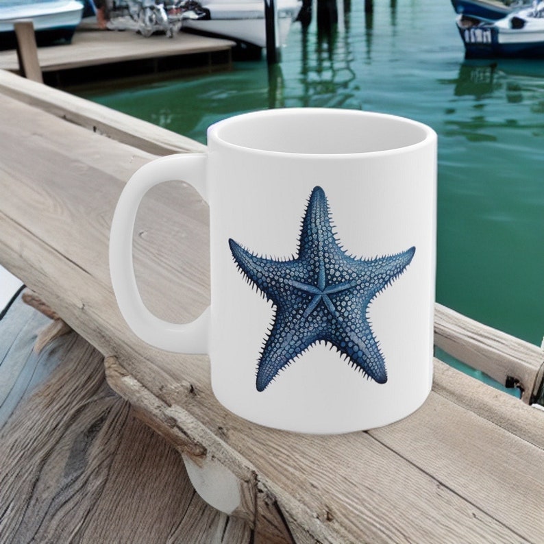 Peut inclure: Une tasse &agrave; caf&eacute; en c&eacute;ramique blanche avec une illustration d'&eacute;toile de mer bleue. L'&eacute;toile de mer a un design textur&eacute; et d&eacute;taill&eacute;.
