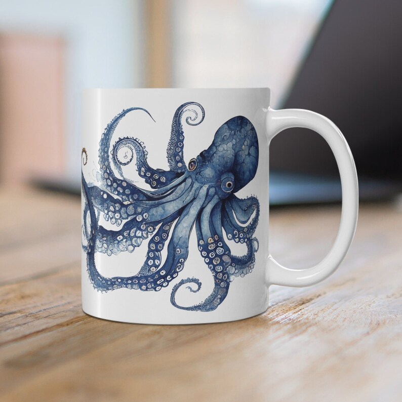 May include: A white ceramic mug with a blue and white octopus illustration. The octopus has eight tentacles and is depicted in a detailed, realistic style.