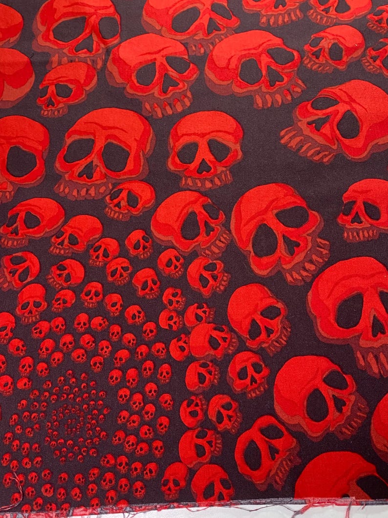 Op de afbeelding: Stof met een rood schedelpatroon en een spiraalvormig ontwerp van kleinere schedels in het midden.