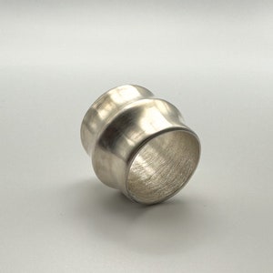 Peut inclure: Une bague en argent avec une finition texturée et martelée. La bague est large et de forme arrondie.