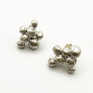 May include: A pair of silver earrings with a cluster of small, round, textured beads. The earrings are in the shape of a small, irregular cluster.