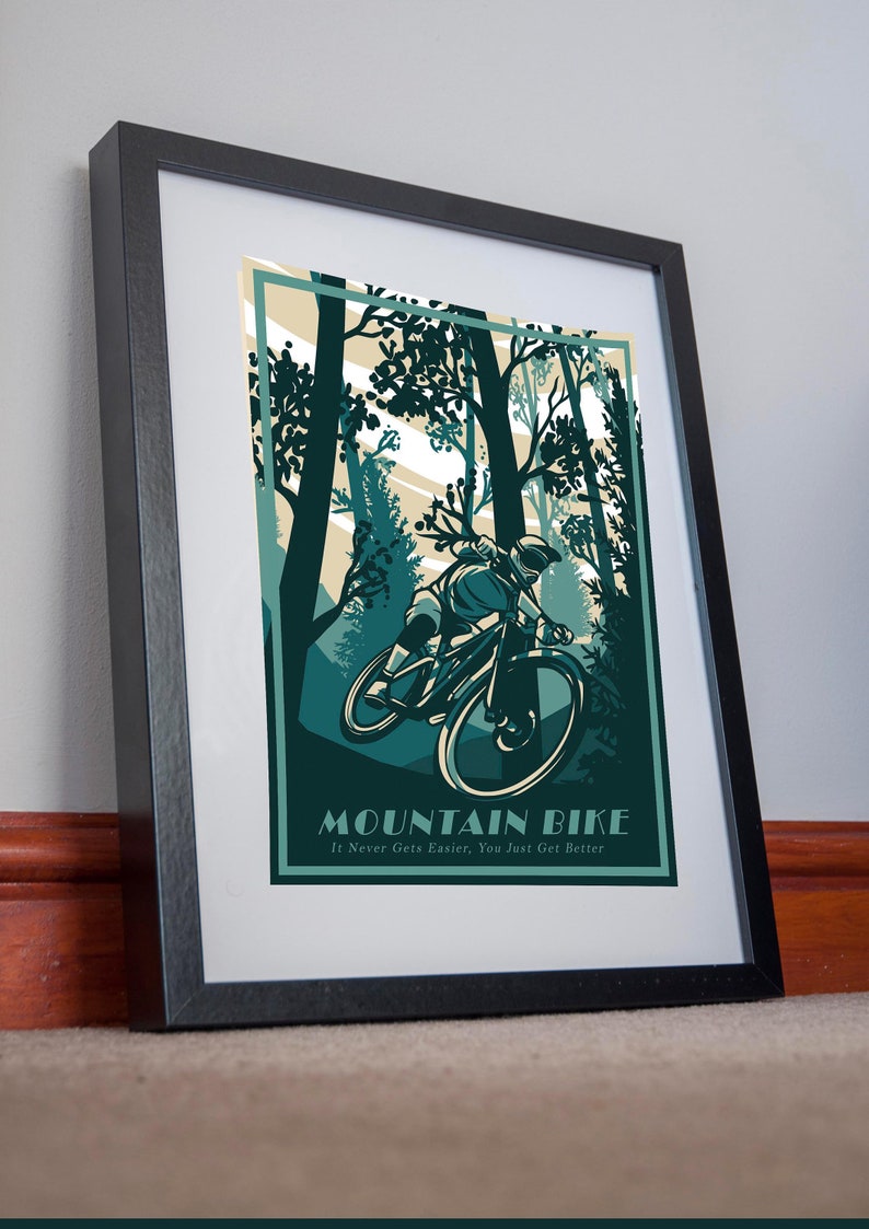 May include: A framed poster with a green and brown illustration of a person riding a mountain bike through a forest. The text "Mountain Bike" is at the bottom of the poster with the tagline "It Never Gets Easier, You Just Get Better".