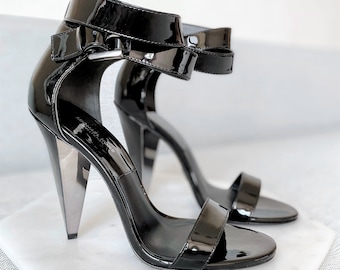 May include: Black patent leather heeled sandals with an ankle strap and a pointed toe.