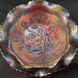 May include: A vintage iridescent glass bowl with a scalloped edge and a raised design of roses. The bowl is in shades of red, pink, and purple.