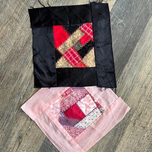 Könnte beinhalten: Zwei Vintage-Quiltblöcke. Der obere Block ist quadratisch, mit einem schwarzen Satinrand und einer Patchwork-Mitte aus roten, goldenen und schwarzen Stoffen. Der untere Block ist rautenförmig und rosa mit einer Patchwork-Mitte aus roten und rosa Stoffen.