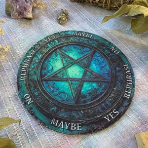 May include: Round teal and black divination board with a pentagram design. The board features the words "Yes", "No", and "Maybe" around the edge, with the word "Rephrase" in between. The board is surrounded by a decorative border.