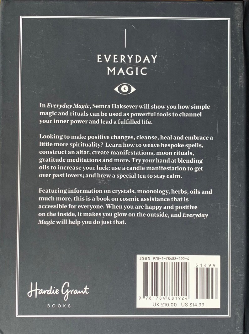 May include: A black and white book cover with the title "Everyday Magic" in white text. The book cover features a stylized eye symbol and text about using simple magic and rituals to channel inner power and lead a fulfilled life. The book is by Semra Haksever and published by Hardie Grant Books.