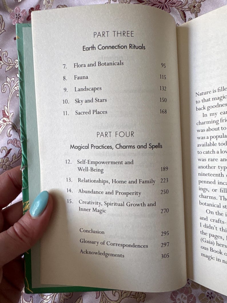 May include: Open book with a green cover, displaying a table of contents. The headings include "Earth Connection Rituals" and "Magical Practices, Charms and Spells." Topics listed are Flora, Fauna, Landscapes, Sky, Stars, and Sacred Places.
