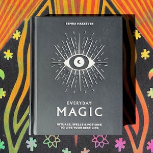 May include: A black book with a white eye and sunburst design on the cover. The title is "Everyday Magic: Rituals, Spells & Potions to Live Your Best Life".