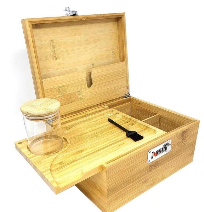 May include: A wooden box with a lock and a tray for rolling. The box has a compartment for storing items and a glass jar with a lid.