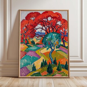 May include: A framed landscape painting with vivid colours. The artwork depicts a winding path through fields of green, purple, and yellow. Towering trees with bright red foliage dominate the top, with a teal tree in the centre. The sky is a pale blue.