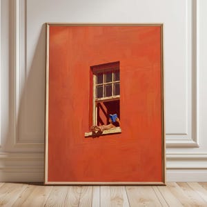 Può includere: Stampa artistica incorniciata raffigurante un'arancione parete con una finestra. Una persona legge un libro blu nella finestra, con i piedi appoggiati sul davanzale. L'opera d'arte è in una cornice dorata, contro un muro bianco e un pavimento in legno.
