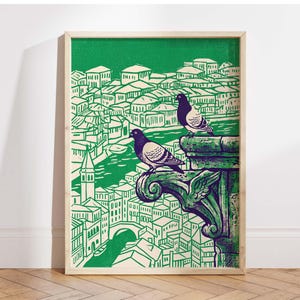 May include: A framed art print featuring a green and white illustration of a cityscape with two pigeons perched on a decorative ledge. The artwork has a vintage, linocut style, with a green background and a light wood frame.