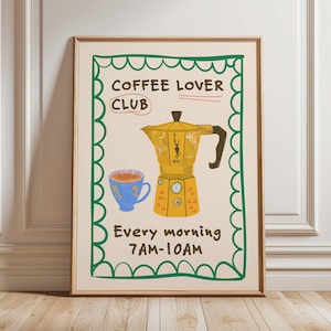 Puede incluir: Una lámina artística enmarcada con una cafetera italiana amarilla y una taza de café azul. El texto dice COFFEE LOVER CLUB y Every morning 7AM-10AM. El diseño está encerrado en un borde verde festoneado sobre un fondo crema con letras marrones.
